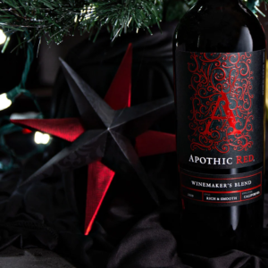 Apothic Wine holiday ornament craft tutorial showing hands wrapping decorative paper with wine bottle and festive holiday decor in background